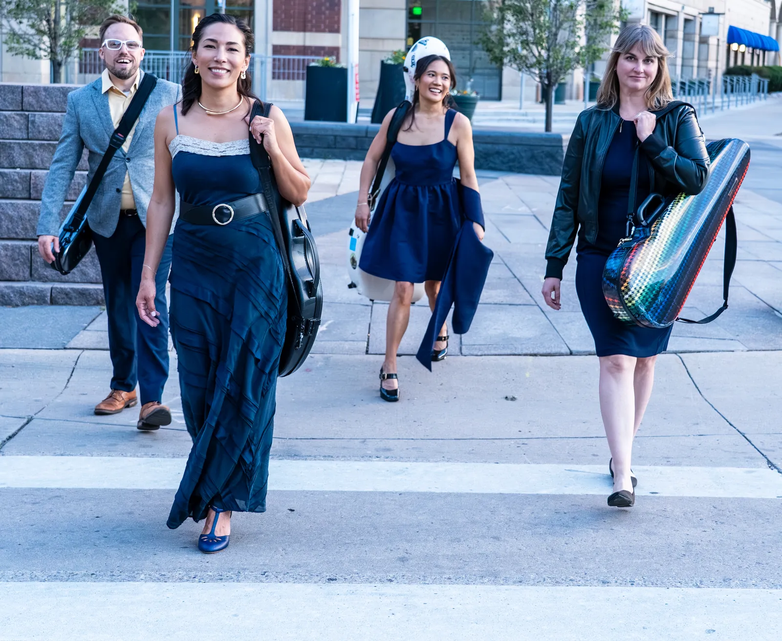 Midnight Post walking through a Denver crosswalk carrying their instrument cases